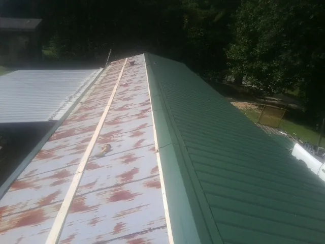 Old rusted panels beside newly installed green metal roofing — Wind Damage Roof Repair by Roofing Brothers in Lyndhurst