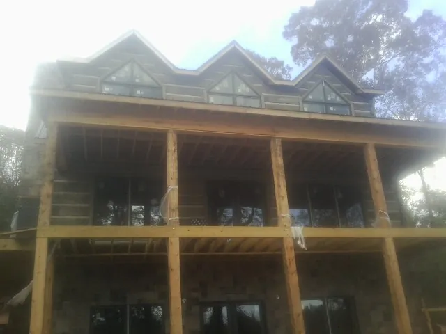 Dormers and porch framing on a large log home under construction — Roof Coating work by our crew in Lyndhurst