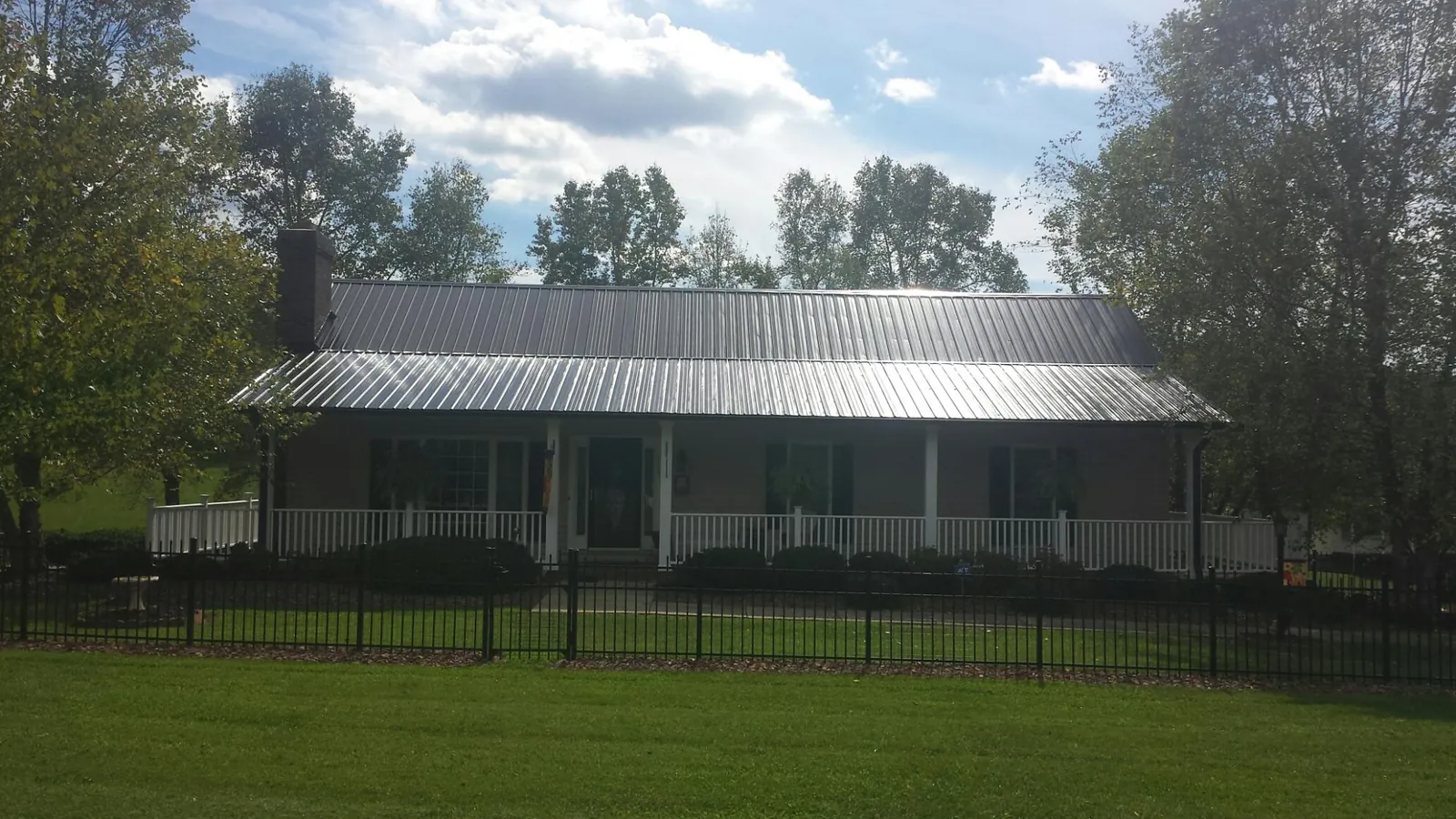 Gray metal roof on a brick ranch with a full width front porch — Gutter Guard Installation work by our crew in Lyndhurst